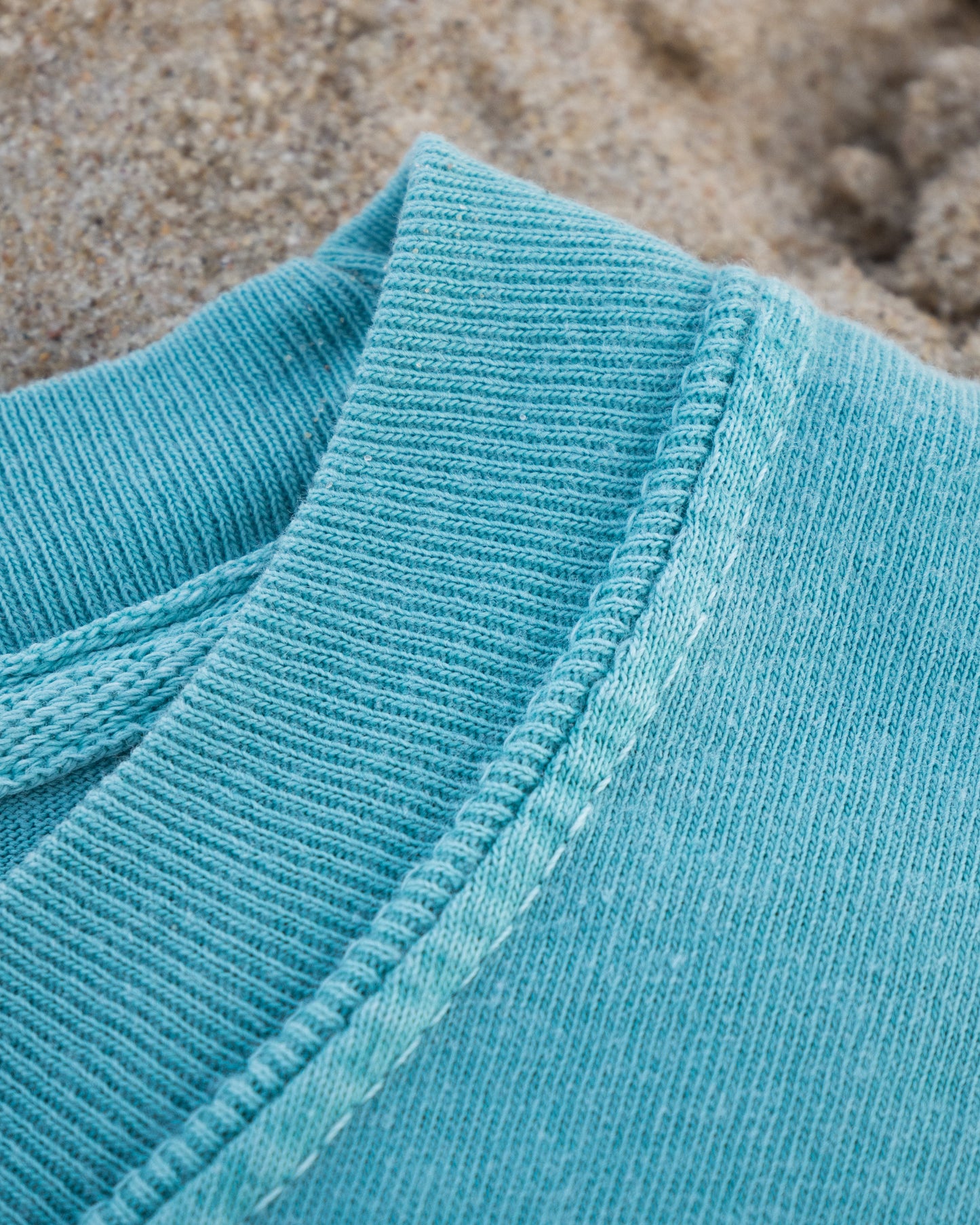 Close-up of a blue textured fabric with sand in the background