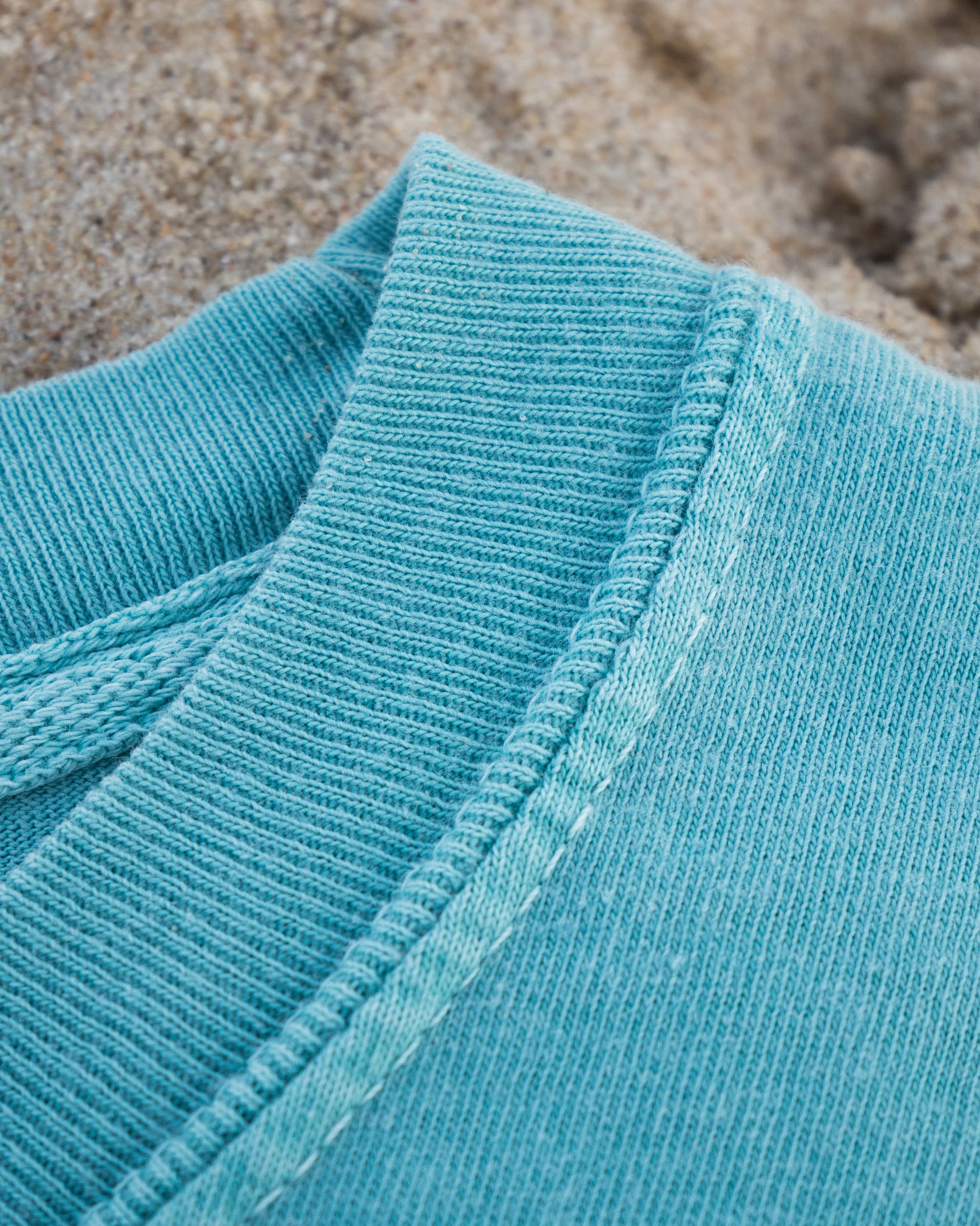 Close-up of a blue textured fabric with sand in the background