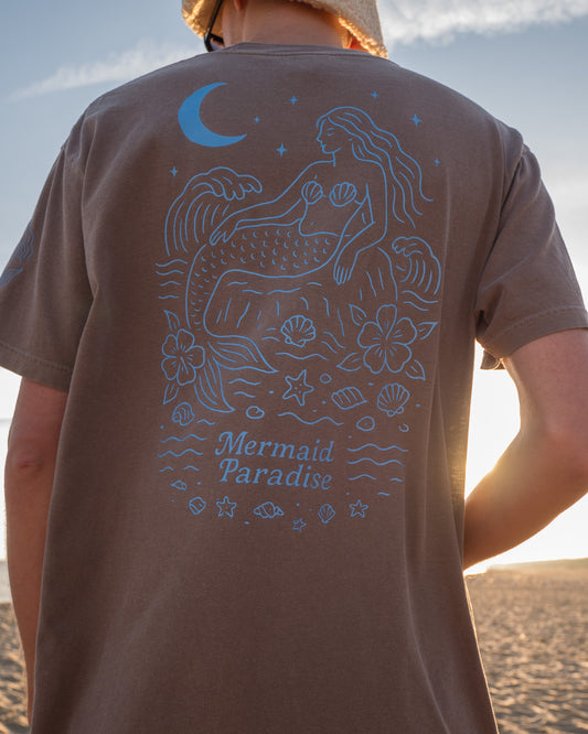 Person wearing a brown t-shirt with a mermaid design on the beach
