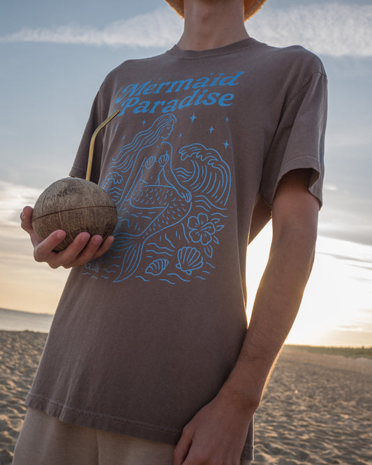 Person wearing a t-shirt with a graphic design on a beach at sunset