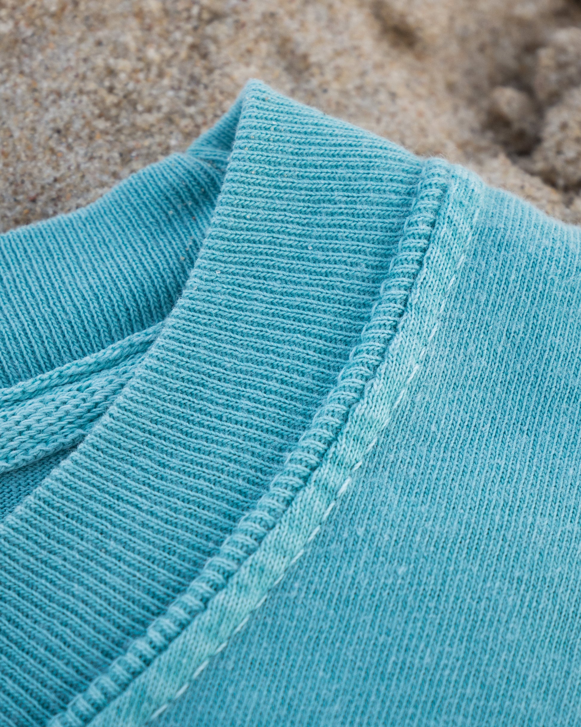 Close-up of a blue textured fabric with sand in the background