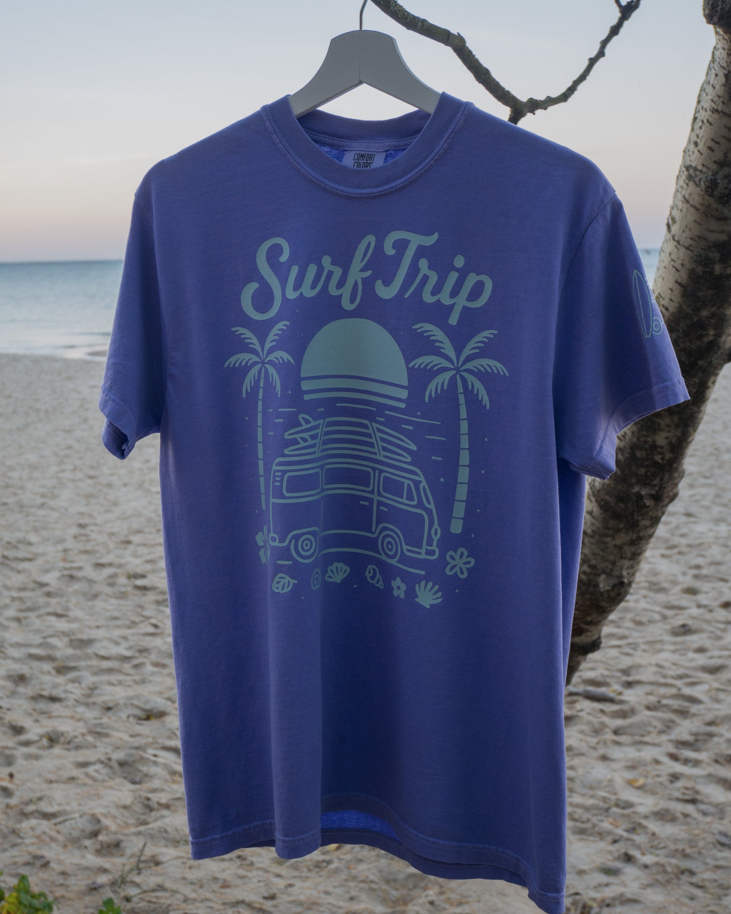 Violet t-shirt with 'Surf Trip' design on a beach